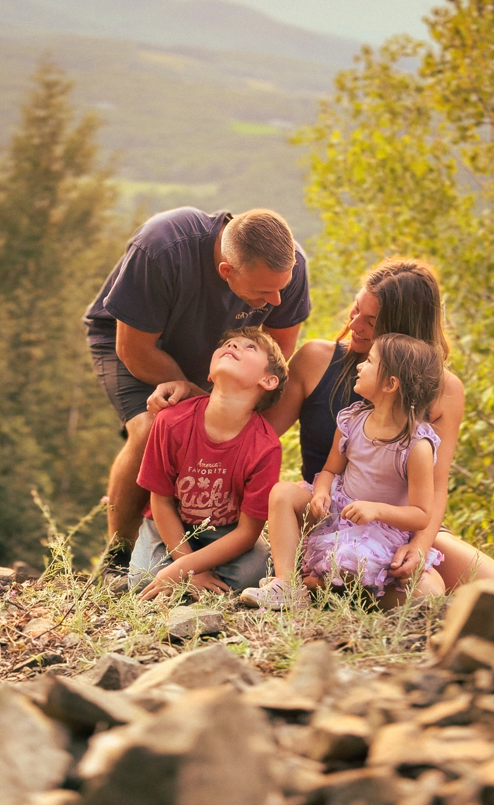 A family sitting together on a hillside at golden hour